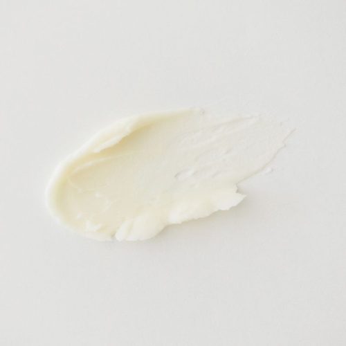Pink rose bud bath salt scattered beside an open glass jar